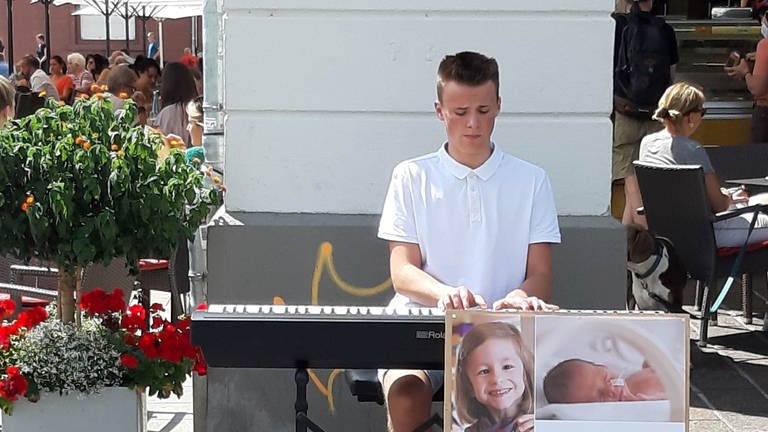 Laurin spielt in der Innenstadt Klavier um Spenden zu sammeln.